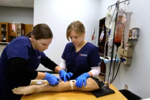 Two medical assistant students practicing taking a blood sample.