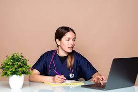An Administrative Medical Assistant looking at a laptop while writing.