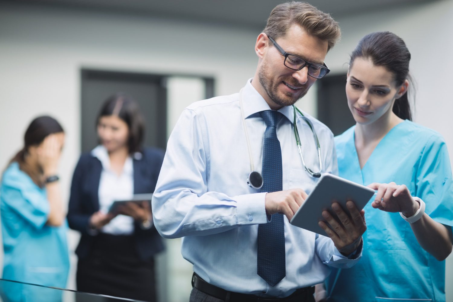Doctor discussing with a medical assistant, with a medical coder in the background.